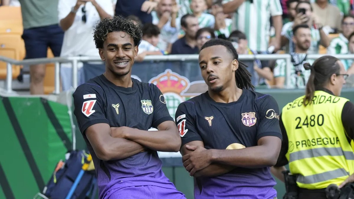Two Barcelona players stand with arms crossed beside the pitch in a recent match, press photo of 17 Oct 2026. Source: The Sporting News.